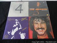 Four vinyl album covers laid out on black fabric, showing each album's front cover.