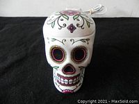 Front view of ceramic skull scented lamp showing colorful floral decoration and electric cord.