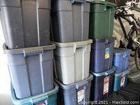 Stacked Rubbermaid storage containers in various colors including grey, blue, green showing overall lot condition and variety.