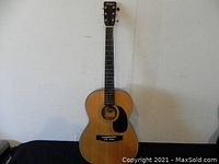 Full view of the vintage El Degas acoustic guitar showing entire front body and neck against a plain white wall.