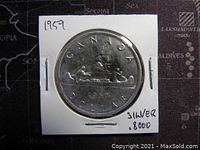 Front side of 1959 Canadian silver dollar showing canoe design with two paddlers, inscribed 'CANADA DOLLAR 1959 SILVER .8000' on white cardboard holder.