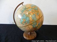 Full view of the globe mounted on a round wooden stand on black background