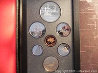 Top-down photo of the seven Canadian proof coins neatly arranged in fitted slots within a black presentation case. Visible designs include a bridge, coat of arms, a beaver, a maple leaf on the penny, and other detailed motifs on silver-colored coins.