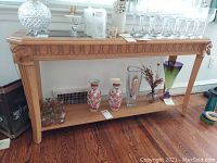 Photo of five vases and six decorated glasses displayed on wooden furniture.