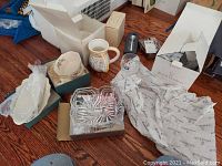 Wide view showing multiple items including wrapped tray, flowered pitcher, stemware wine glasses, mixer, silver-plated honey dish, and assorted boxed items.