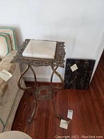 Full view of metal end table with marble top next to sofa and brown marble slab.