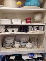Shelf display of Corelle Thistle plates, cups, mugs, sugar bowl and creamer
