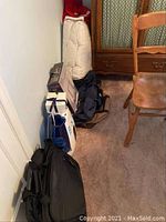 View of the lot showing large rolled-up comforter, several bags, and boxes stacked against wall near wooden furniture.