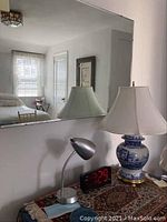 View of the lamps, digital clock, and mirror on a wooden dresser with room reflection