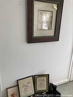 Three framed wall art pieces displayed on and against a white wall, showing relative sizes and styles.