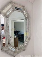 Full view of octagonal mirror hanging on a white wall showing surrounding room reflections.