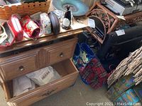 Wooden two-drawer cabinet with items placed on top and open bottom drawer showing contents inside the drawer not included