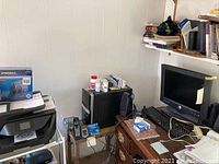 Photo showing a corner desk setup with 17-inch Dell monitor, black tower computer, wired keyboard and mouse, cordless phone, Sabrent HD enclosure box and a black desk lamp.