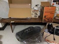 Wood bench with boxes and other items placed on top, showing overall shape and length.