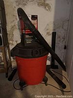 Photo of red and black Sears Craftsman wet dry vacuum with hoses attached, showing the main vacuum unit on wheels.