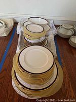 Multiple stacks of plates with cobalt and gold trim, plus serving bowl and platter beneath