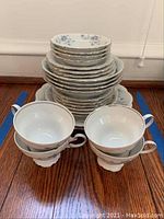 Stack of plates with similar pattern and two matching teacups in front