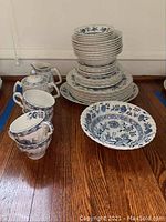 Photo of stacked Blue Fjord Ironstone dinnerware set on wooden surface including plates, bowls, teacups, and a teapot