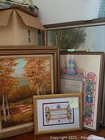 Group photo showing the framed forest scene with autumn foliage, restoration certificate, and another framed artwork behind them.