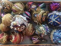 Overview of 23 assorted vintage Christmas ornaments showing a range of sizes and multicolored sequins, beads, and metallic thread designs.