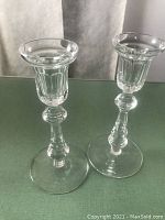 Pair of clear crystal candlesticks with vertical cuts and hexagonal stem detail on green cloth background.
