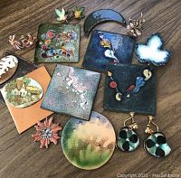 Full lot laid out showing the various enameled pieces including squares, round, floral, cottage and oval designs along with earrings and pins.