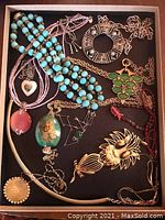 Full view of 11 vintage necklaces in tray, shows varied styles and vivid colors including blue, green, pink, gold, red