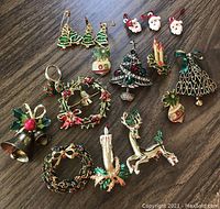 Photo showing full collection of Christmas pins, earrings, ring, and charms arranged on a wooden surface.