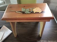 Full view of the footstool showing the wooden structure and hand-painted artwork of a yellow rose and book labeled 'Poetry' on top.