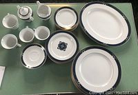 Full set arranged showing cups, covered sugar bowl, creamer, plates, and platter with visible blue and gold decorative pattern