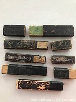 Photo showing five antique razor boxes with visible brand markings and worn black exteriors