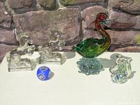 Five art glass pieces displayed outdoors against stone backdrop: 12" duck sculpture, glass squirrel, two pressed glass horse bookends, millefiori paperweight.