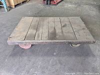 Top view of industrial cart showing oak wood plank platform on steel frame with wear and surface dirt.