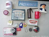 Overview photo showing assorted vintage advertising items including tins, mugs, signs, and collectibles.