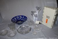 View of Kosta Boda box with two clear crystal candlesticks showing heart half design, assorted clear glass and crystal bowls, a cobalt blue cut glass bowl, and small glass pieces