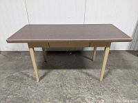 Front view of the COLE Steel tanker table desk showing the wood grain laminate top and beige metal legs.