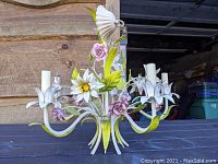 Front view of chandelier on black table showing five arms and floral motifs