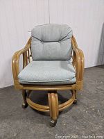 Front view of Lane Venture rattan desk chair with blue cushions on wooden floor.
