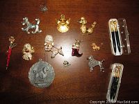Top-down view of all lot items on wooden surface showing pins, brooches, ring, pewter medal, and two pen sets in cases