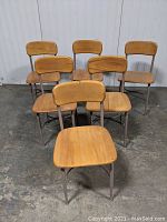 Front view of six wooden school chairs with light beige metal frames arranged in two rows.