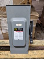 Gray metal heavy-duty safety switch with handle and safety labels.