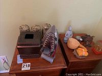 Shark iron sitting on wooden box alongside Buddha statue, bird figurine, wooden bowl, red glass candle holder, and other art items.