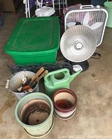 Photo showing Presto Heatdish heater, Lasko box fan, green storage bin, garden tools in bucket, plant pots, and garden borders