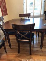 Full view of wooden dining table with six chairs, showing furniture style and condition.