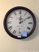 Photo of round wall clock with dark wood frame, white face, Roman numerals, clock hands, brand name 'L'Epoque London'