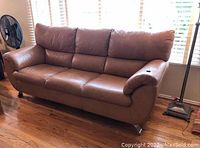 Front view of beige leather sofa showing three-seat layout and padded arms