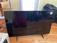 Front view of the TV on stand showing screen and overall condition