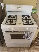 Front view of the white Frigidaire gas stove showing the four burners on top, oven door with window, and control knobs.