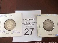 Two Newfoundland 20 cent coins, dated 1894 and 1882, displayed side by side in protective holders over auction sign.