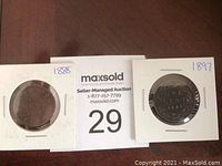 Two large Canadian one cent coins in protective holders, dated 1886 and 1897, laid flat on table with auction placard.